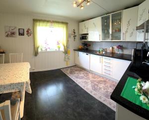 a kitchen with white cabinets and a table and a window at Gjesterom til leie i et privat hus 250 moh in Brumunddalen