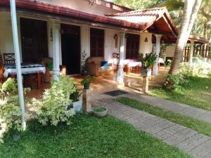 a porch of a house with a table and chairs at Rio Lake Hotel Sigiriya in Habarana