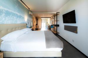 ein Schlafzimmer mit einem weißen Bett und einem Flachbildfernseher in der Unterkunft Spa Hotel Splendid Sole in Manerba del Garda