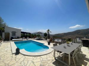 eine Terrasse mit Pool, Tisch und Stühlen in der Unterkunft Casita Risa in Viñuela