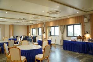 a conference room with blue tables and chairs at The Bhavani Hotel in Dāhod