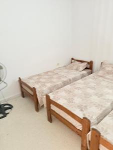 two twin beds in a bedroom with a fan at Appartement de plage d in As Suwaysah