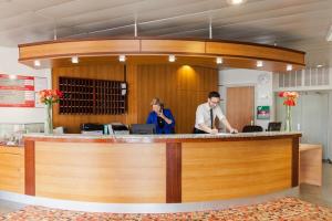 a man and a woman standing at a counter in a practition at The Originals City, Hôtel Le Forum, Strasbourg Nord in Schiltigheim