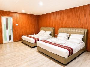 two beds in a room with orange walls at SS Hotel Seremban in Seremban