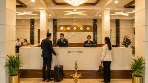 a man and woman with luggage standing at a reception counter at Hotel Indraprasttha in Vijayawāda