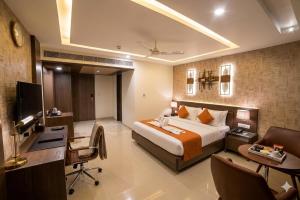 a hotel room with a bed and a desk and a computer at Hotel Indraprasttha in Vijayawāda