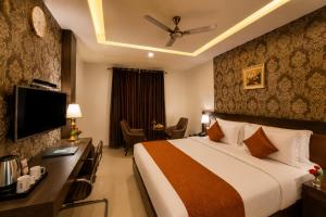 a hotel room with a bed and a desk with a television at Hotel Indraprasttha in Vijayawāda +20 photos