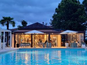 a swimming pool with chairs and umbrellas next to a house at Residence Duna Rossa - Family Friendly in Duna Verde