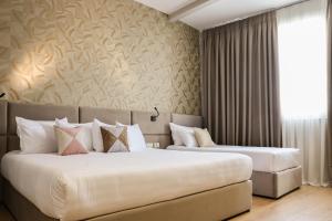 two beds in a hotel room with a wall at Best Western Plus The Met Tirana Hotel in Tirana