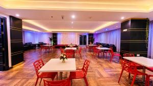 a dining room with tables and red chairs at Amber Tower in Al Ghurayfah