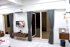 a hotel room with a television and a bedroom at Infinity Hotel in Rajkot