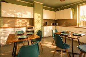 a kitchen with two wooden tables and green chairs at Leipzig Garden Rooms - Near Lake & easy Parking in Leipzig