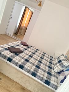 a bed in a room with a plaid blanket at Cosy luxury apartament in Baia Mare