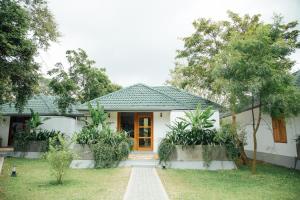 a small white house with a door in a yard at vainika wild sigiriya in Sigiriya