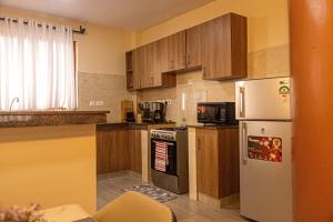a kitchen with wooden cabinets and a white refrigerator at PrimeCitySuites in Nakuru