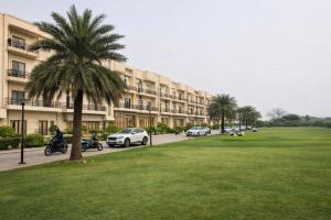 a palm tree in front of a large building at Onyx Suite Luxury Apartment # Lift # Garden # Ac rooms # Private Parking # Near Prem Mandir # Located Inside- Omaxe Eternity Vrindavan # in Vrindāvan