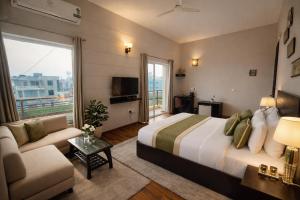 a hotel room with a large bed and a couch at Onyx Suite Luxury Apartment # Lift # Garden # Ac rooms # Private Parking # Near Prem Mandir # Located Inside- Omaxe Eternity Vrindavan # in Vrindāvan