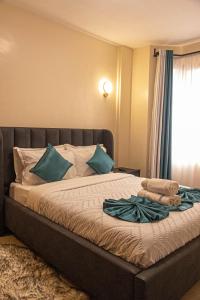 a bedroom with a bed with blue pillows and a window at PrimeCitySuites in Nakuru
