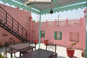 a patio with tables and chairs and a pink building at Ardas Villa Bikaner - Heritage Luxury Boutique Stay, With Free Pick Up and Drop in Bikaner