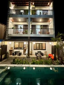a house with a swimming pool in front of a building at Maison De Hoi An Boutique Homestay in Hoi An