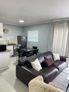 a living room with a leather couch and a kitchen at Blouberg Beach Gem 5 Min Walk in Cape Town