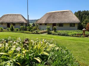 two houses with thatched roofs and a garden with flowers at Otters Den in Nottingham Road