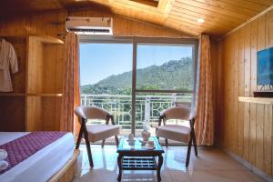 a bedroom with a bed and two chairs and a large window at Royal Nest in Kasauli