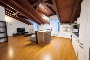 a kitchen and living room with wooden ceilings and a living room at L'Archè - The Rustic Loft in Cinisello Balsamo
