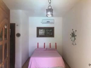 a small bedroom with a pink bed with a window at Châle guesthouse in Paracuru