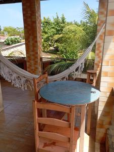a hammock on a porch with a table and chairs at Châle guesthouse in Paracuru