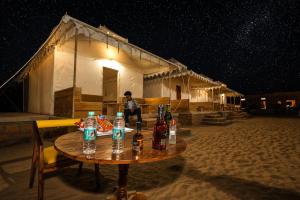 a table with bottles on it in front of a house at Desert Popular Resort & Camp in Jaisalmer