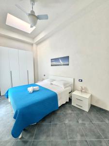 a white bedroom with a blue bed and a nightstand at L'angolo blu in Marettimo
