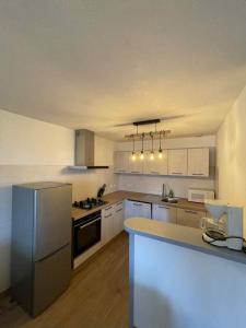 a large kitchen with white cabinets and a refrigerator at Appartement à Vouglans in Lect