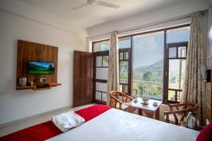 a bedroom with a bed and a table with a television at Royal Nest in Kasauli +5 photos