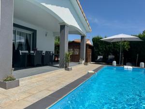 a swimming pool with an umbrella next to a house at Chambre d'hôtes in Montauban