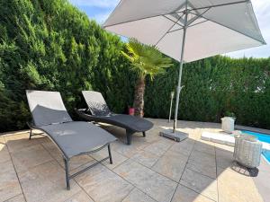 a patio with two chairs and an umbrella at Chambre d'hôtes in Montauban
