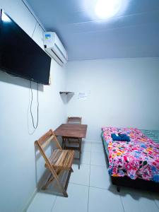 a bedroom with a bed and a table and a tv at Suítes Jacumã in Conde