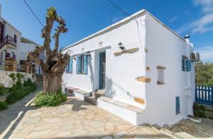 a white house with a tree in front of it at Xenia Xinara in Tinos