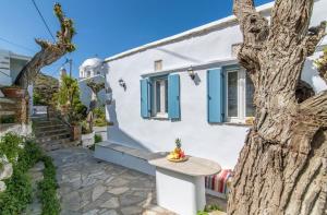 a white house with a table and a tree at Xenia Xinara in Tinos