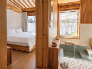 a bedroom with a bed and a tub and a window at Hanokstay mokhwa in Gyeongju