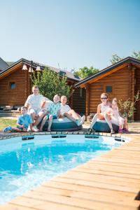 a group of people sitting on inflatables by a swimming pool at SkyFrame cottage with pool in Plav