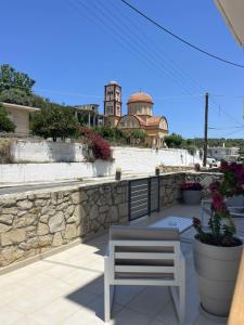 a white chair sitting on a patio with a stone wall at Amare casa in Perivólia