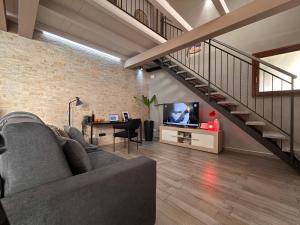 a living room with a couch and a tv and a staircase at The Hangar Loft - Leonoardo, Center & Parking in Sesto Calende