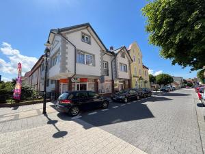 a street with cars parked in front of a building at Pokoje ABC Centrum in Ustka