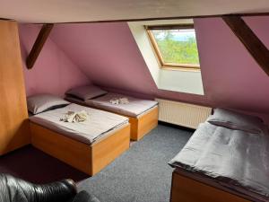 a attic room with two beds and a window at Penzion Nord in Hora Svatého Šebestiána
