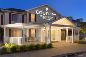 Country Inn & Suites by Radisson, Nevada, MO في Nevada: مبنى فيه نزل واجنحه ريفيه توقع عليه