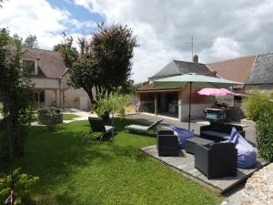 a backyard with a patio with chairs and an umbrella at Au long du cher in Véretz +5 photos