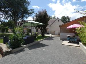 a patio with a table and a green umbrella at Au long du cher in Véretz