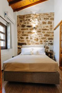 a bedroom with a bed with a stone wall at Rustic Kampos House Retreat in Chios