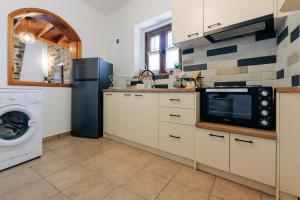 a kitchen with a refrigerator microwave and a washer and dryer at Rustic Kampos House Retreat in Chios